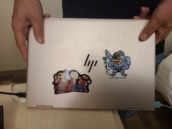 Nice Disc and Kairiki (Machamp) stickers on a shiny metallic pink HP laptop
